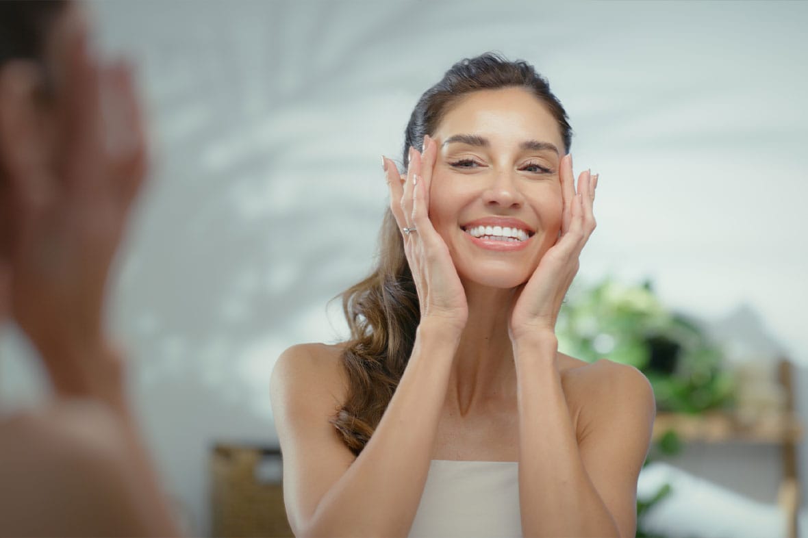 woman smiling looking in the mirror after her facelift in Manhattan