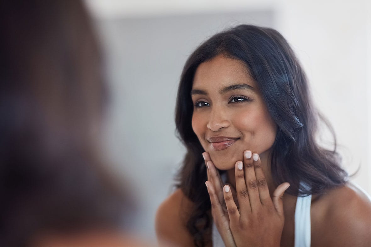 woman looking in the mirror after getting a SMAS facelift in NYC