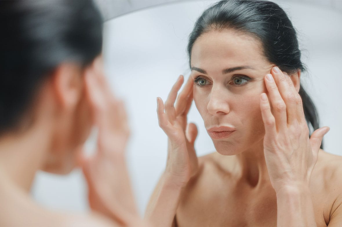 woman looking in the mirror after her facelift in NYC