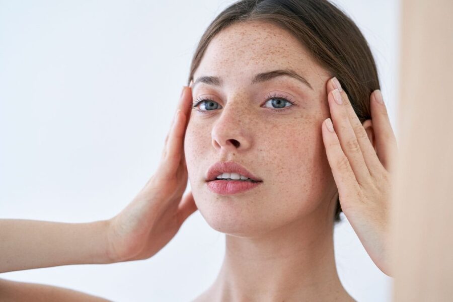 woman looking in the mirror after her rhinoplasty in NYC