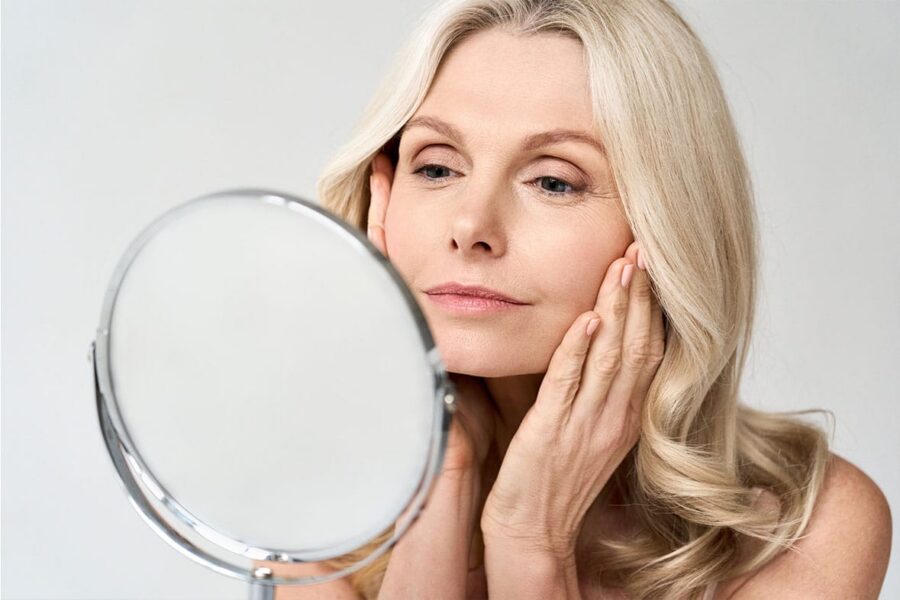 older woman looking in the mirror after her deep plane facelift in NYC