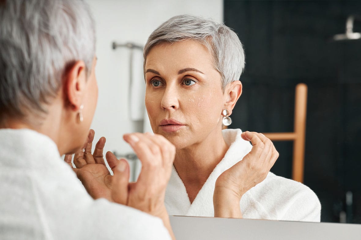 older woman looking in the mirror after her facelift in NYC