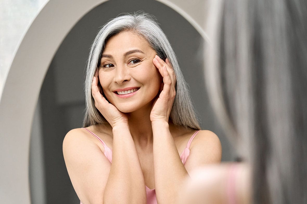 older woman looking in the mirror after her revision facelift in New York City