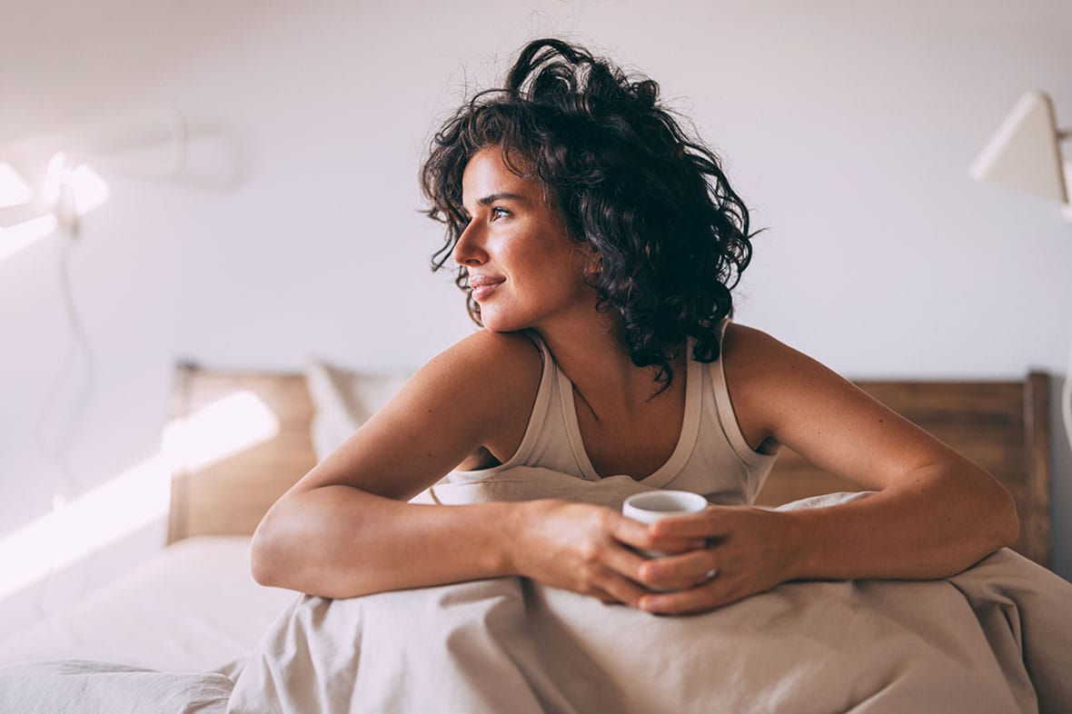 woman in bed smiling after her functional rhinoplasty in NYC