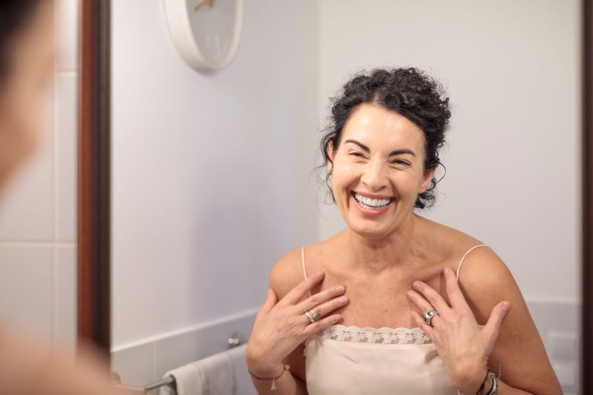 older woman smiling in the mirror after her facelift in NYC